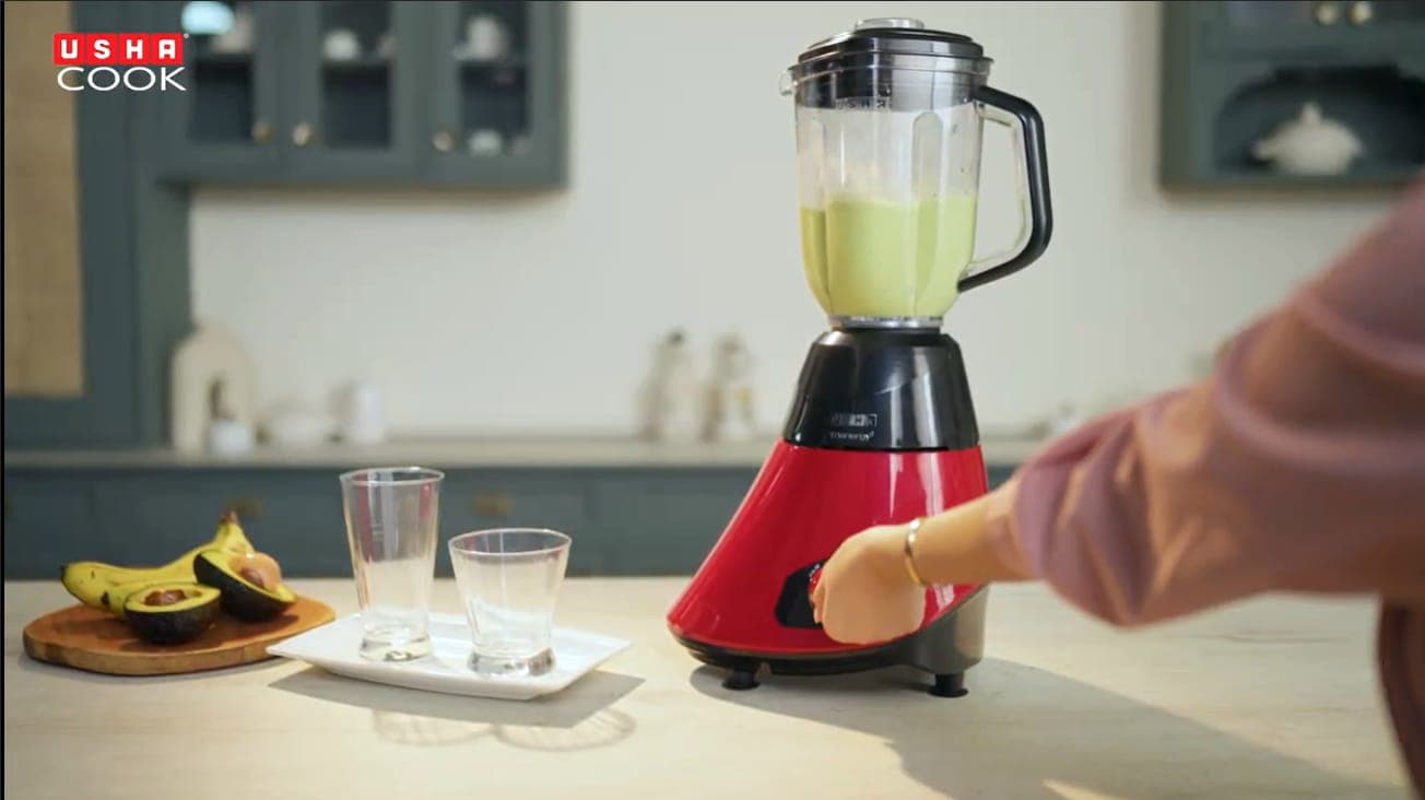 Hand on the dial of a red Usha blender